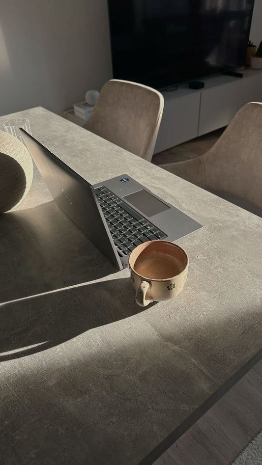 Laptop con tienda Shopify abierta sobre una mesa con café, representando un sitio web bonito que no convierte en ventas